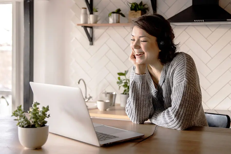 Smiling woman talking via laptop in kitchen 4049992