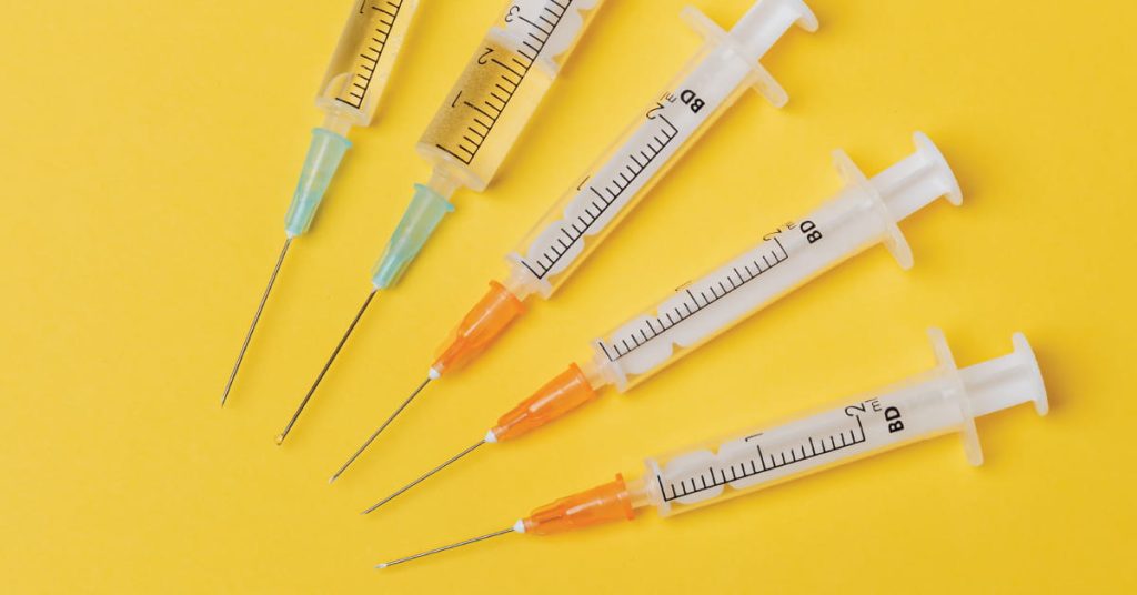 Syringes of different sizes on yellow background - FI